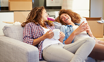 Two young ladies relaxing in a sofa in a newly bought home