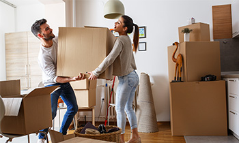 Young couple moving into a new home. Surrounded by cardboard boxes.