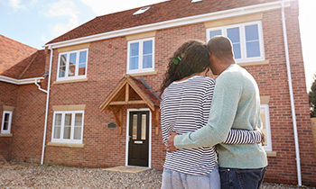 A young couple stood outisde looking a their new build home